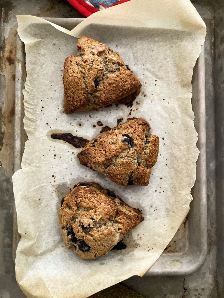 Three blueberry buckwheat scones on a sheet tray